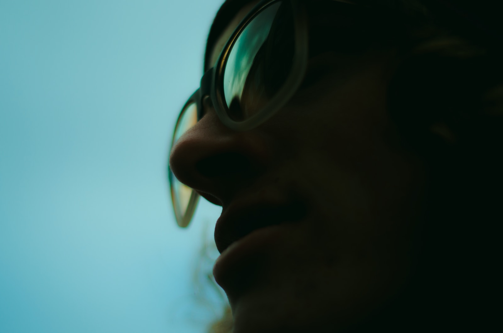 swkpcfbrhvc close up photo of person wearing glasses with teal background